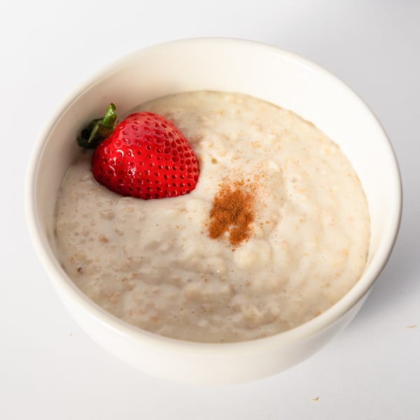 A bowl of Mervis' Cafe oatmeal with a fresh strawberry and a sprinkle of cinnamon.