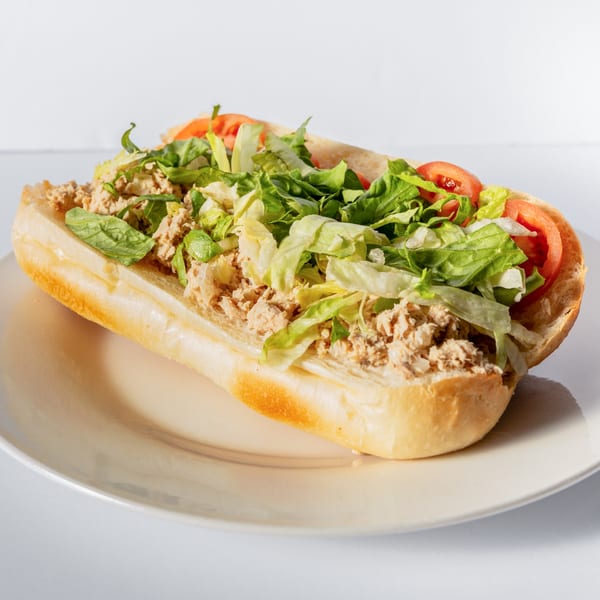 A Mervis' Cafe Cuban tuna sub with lettuce and tomato on a white plate.