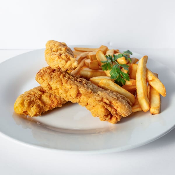 Crispy fried chicken tenders and golden french fries garnished with fresh parsley on a white plate.