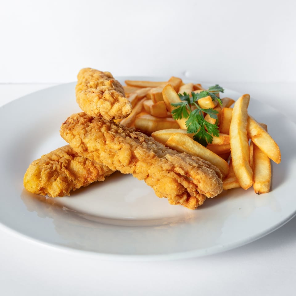Crispy fried chicken tenders and golden french fries garnished with fresh parsley on a white plate.