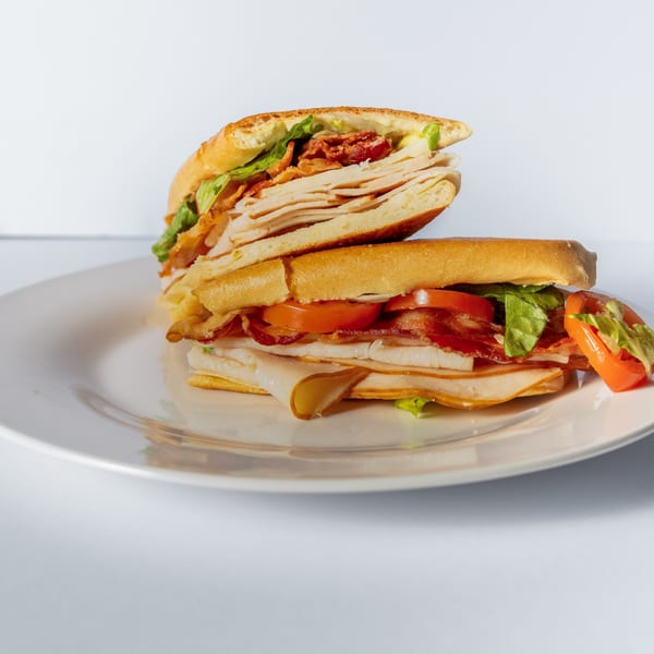 Mervis' Cafe Cuban sandwich with turkey, bacon, lettuce, and tomato on a white plate.